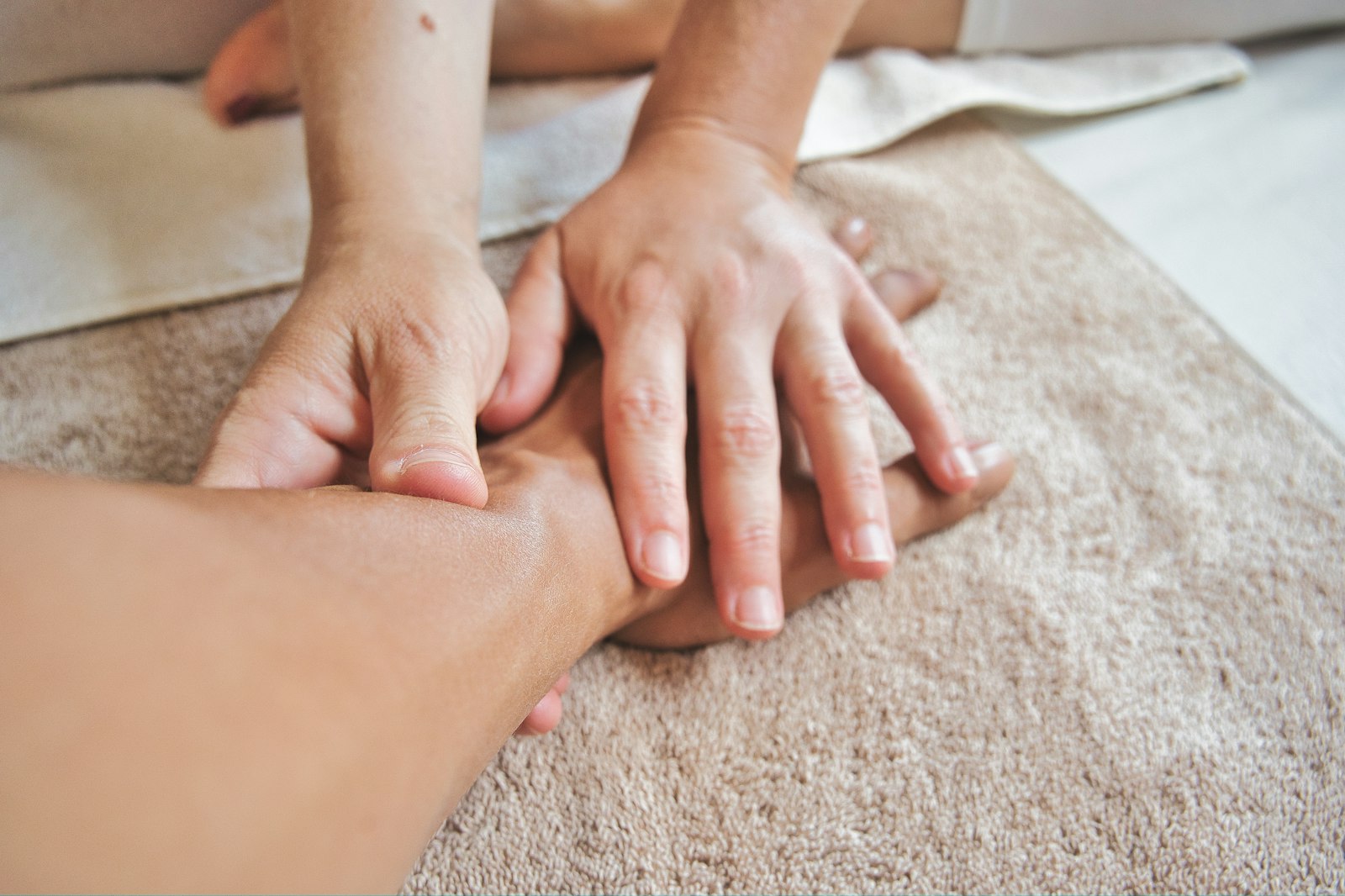 Deux mains pratiquant un massage manuel sur une serviette claire